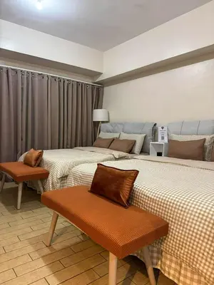 a room with three beds and a bench in it at Staycation in Manhattan near Smart Araneta in Manila