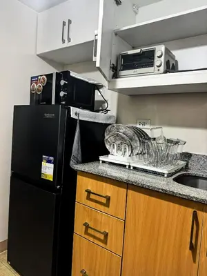 a kitchen with a black refrigerator and a sink at Staycation in Manhattan near Smart Araneta in Manila