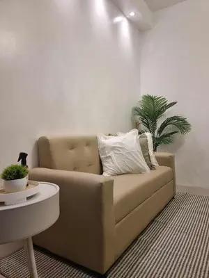 a couch in a living room with a plant at 1569 Shore Residences MOA in Manila