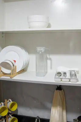 a kitchen shelf with plates and utensils on it at Relaxing 1BR Balcony with Pool View Plus Free Parking in Manila