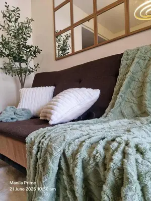 a bed with a blanket and pillows and a mirror at 1586 Shore Residences tower C2 in Manila