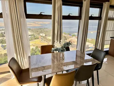 a dining room with a table and chairs and large windows at The Grand Lower Penthouse 2 Bedrooms, 3 Baths in Manila