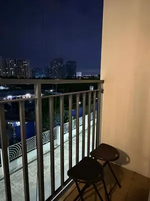 a balcony with two chairs and a city skyline at night at Twin Bed 1BR w Balcony with WiFi Netflix at Shore2 T1 near MOA and NAIA Airport in Manila