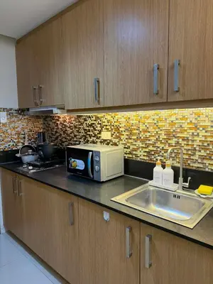 a kitchen with a microwave and a sink at Neo-Classic 1BR with WiFi Netflix at Shell Res near MOA and NAIA Airport in Manila