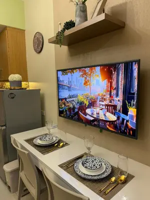 a tv hanging on a wall above a dining room table at Neo-Classic 1BR with WiFi Netflix at Shell Res near MOA and NAIA Airport in Manila
