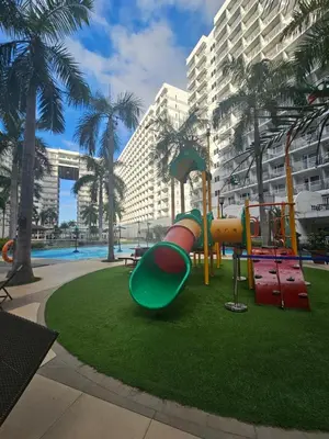 a playground in front of a large building with palm trees at Neo-Classic 1BR with WiFi Netflix at Shell Res near MOA and NAIA Airport in Manila