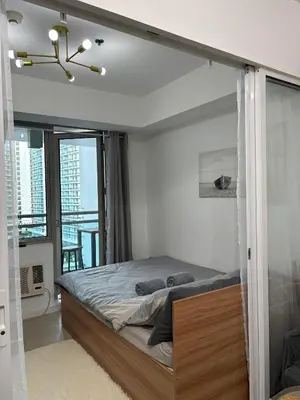 a bedroom with a bed and a balcony at Anasa Suites in Manila