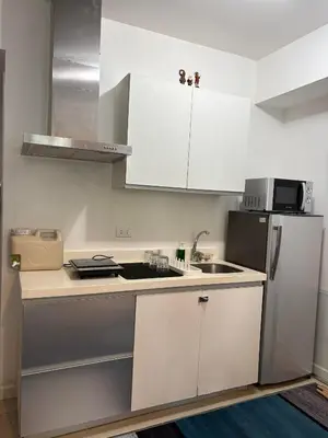 a kitchen with white cabinets and a sink and a refrigerator at Anasa Suites in Manila