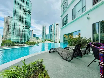 a swimming pool with chairs and a building with tall buildings at Cozy Stay 3 min to Rockwell City View Pool Parking in Manila