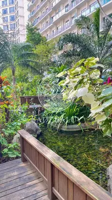a garden with a pond in front of a building at Cozy Stay 3 min to Rockwell City View Pool Parking in Manila