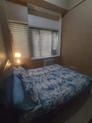 a bedroom with a bed with a blue blanket and a window at Cozy Condo Across NAIA T3 One Palm Tree in Manila