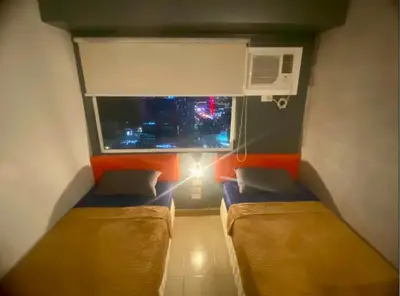 a small room with two beds and a window at Azure Haven in Manila