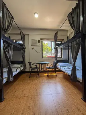 a room with two bunk beds and a table and chairs at The Budget Inn in Manila