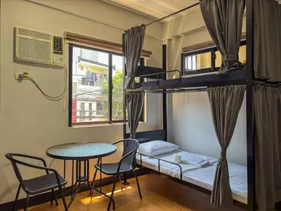 a bedroom with a bunk bed and a table and chairs at The Budget Inn in Manila