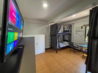 a living room with a flat screen tv and a bedroom at The Budget Inn in Manila