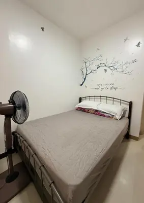 a bedroom with a bed with a fan and a wall at LA Nook in Manila