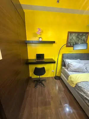 a bedroom with a bed and a desk with a laptop at Sunbeam - Lush Residence in Manila