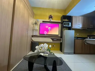 a kitchen with a table and a tv on a wall at Sunbeam - Lush Residence in Manila