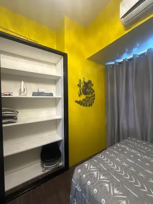 a bedroom with a bed and a yellow wall at Sunbeam - Air Residence 45th floor in Manila