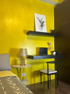a yellow room with a bed and a table and chairs at Sunbeam - Air Residence 45th floor in Manila