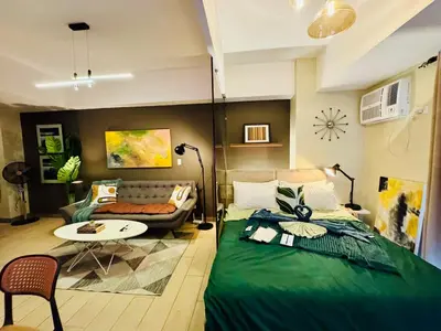 a bedroom with a green bed and a couch at Cozy unit with balcony Netflix walk to Venice Mall in Manila