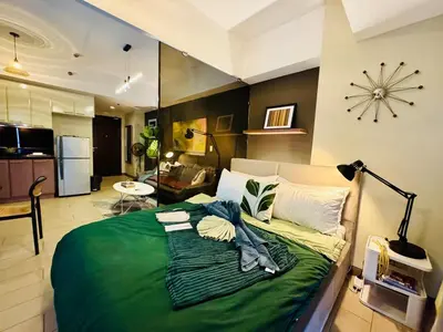 a bedroom with a large green bed in a room at Cozy unit with balcony Netflix walk to Venice Mall in Manila