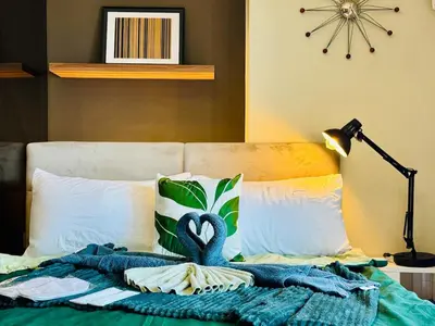 a bed with a blue blanket and a swan on it at Cozy unit with balcony Netflix walk to Venice Mall in Manila