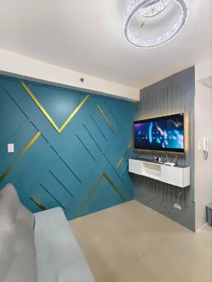 a living room with a blue wall with a tv at La Casa Victoria-Near Moa and NAIA in Manila