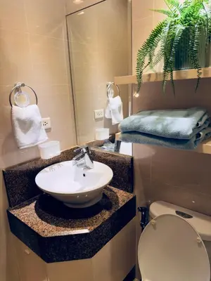 a bathroom with a sink and a toilet and a mirror at Chic Eastwood City Studio w Pool and Gym Access in Manila