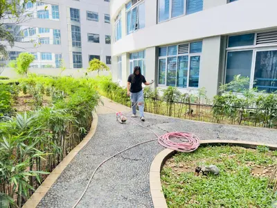 a woman walking two dogs on a path in front of a building at Chic Eastwood City Studio w Pool and Gym Access in Manila