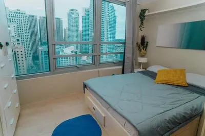 a bedroom with a bed and a large window at Chic Eastwood City Studio w Pool and Gym Access in Manila