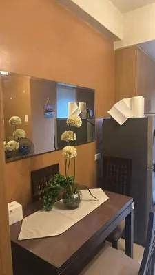 a dining room table with a vase of flowers on it at Shell Residences Moa AJ in Manila