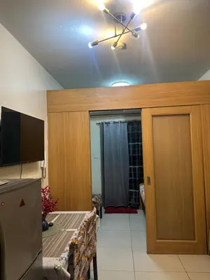 a living room with a table and a ceiling fan at Shell Residences Moa AJ in Manila
