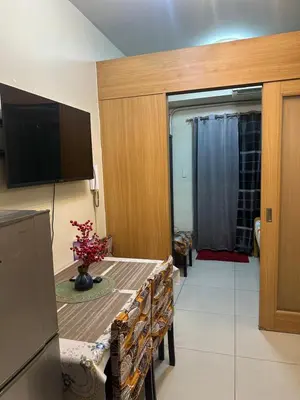 a kitchen with a table with chairs and a television at Shell Residences Moa AJ in Manila