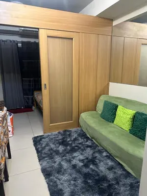 a living room with a green couch and a door at Shell Residences Moa AJ in Manila