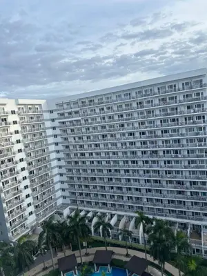 a large apartment building with a pool and palm trees at Shell Residences Moa AJ in Manila