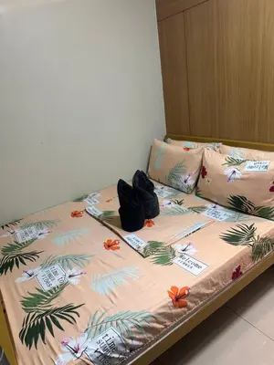 a bed with flip flops on it in a room at Shell Residences Moa AJ in Manila