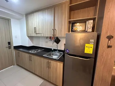 a kitchen with a stainless steel refrigerator and wooden cabinets at Affordable Condotel Stay in Pasay, MOA Complex in Sampong