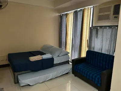 a bedroom with a bed and a couch and a window at Cozy Studio Viceroy Residences in Manila