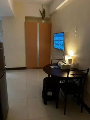 a room with a table and chairs and a tv at Cozy Studio Viceroy Residences in Manila