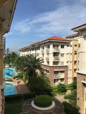 an apartment building with a pool and palm trees at Cozy 2BR at an Italian inspired condo near Ortigas in Manila