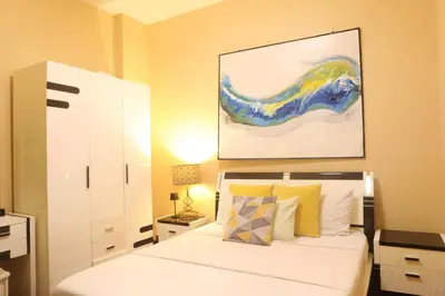 a bedroom with a bed and a painting on the wall at The Mosaic Tower in Manila