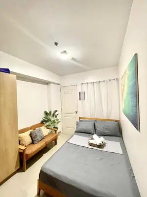 a bedroom with a bed and a couch at AzurestaycationbyGS in Manila