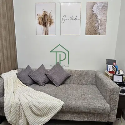 a living room with a couch and pictures on the wall at 1BR Pool View Balcony Near MOA Shore 2 Tower 1 in Manila