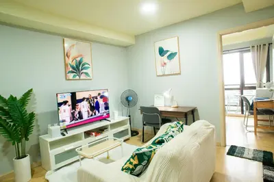 a living room with a white couch and a tv at Nature Serenity Suites 2BR Makati in Manila