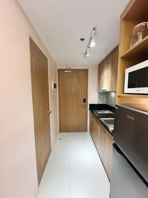 a kitchen with wooden cabinets and a microwave at The Ritz Place at Shore 3 Residences in Manila