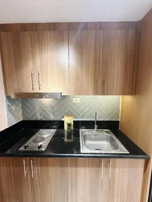 a kitchen with a sink and wooden cabinets at The Ritz Place at Shore 3 Residences in Manila