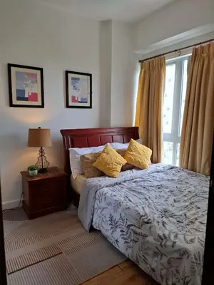 a bedroom with a bed with yellow pillows and a window at Cozy Hotel-Style 1 Bedroom Unit 5L at Eastbay Residences by Rockwell in Manila