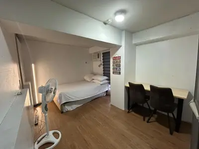 a room with a bed and a desk and chairs at Ports Avida San Lazaro Condo in Manila