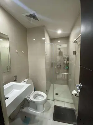a bathroom with a shower and a toilet and a sink at Vienna Condotel in Manila